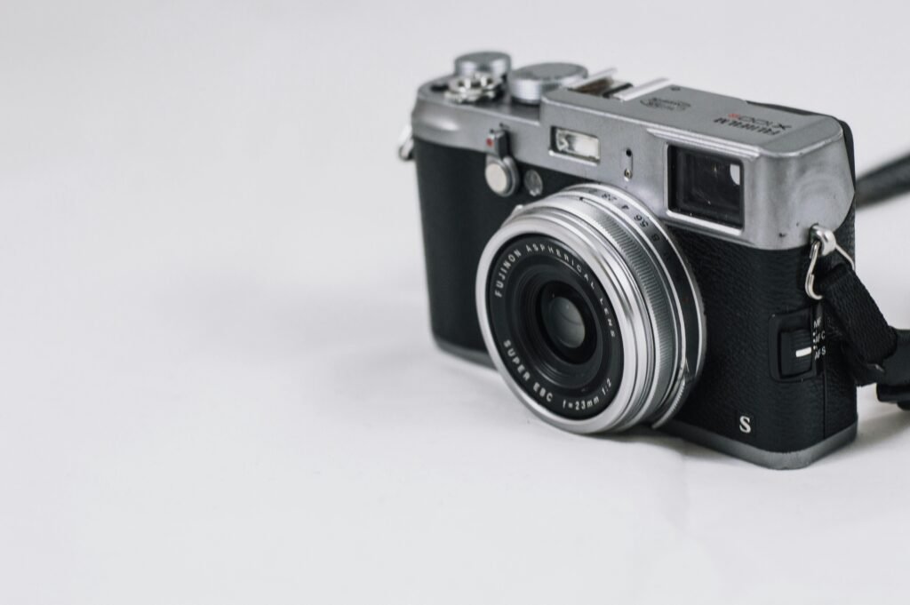 Close-up of a classic vintage rangefinder camera with a retro design on a plain background.